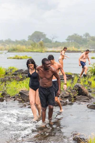 Livingstone Adası, Zambiya - 14 Ocak 2016: Kimliği belirsiz turistler, İskoç kaşif David Livingstone'un adını taşıyan Livingstone Adası'ndaki Zambezi nehrinde yüzmek üzere,