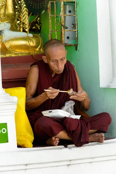Yangon, Myanmar - 24 Ağustos 2016: Tanımlanamayan Birmanyalı Budist keşiş yerel bir tapınakta yemek yiyor. Myanma halkının yüzde 68'i Bamar etnik grubuna mensandı