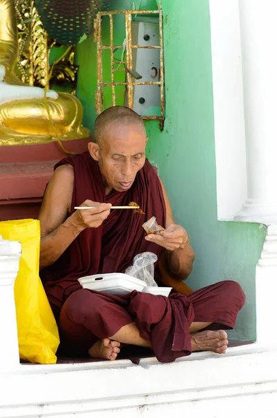 Yangon, Myanmar - 24 Ağustos 2016: Tanımlanamayan Birmanyalı Budist keşiş yerel bir tapınakta yemek yiyor. Myanma halkının yüzde 68'i Bamar etnik grubuna mensandı