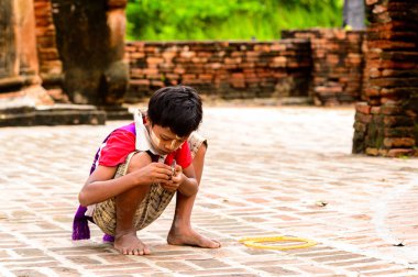 Inwa, Myanmar - 25 Ağustos 2016: Tanımlanamayan Birmanyalı genç çocuk yerde oynuyor. Myanma halkının yüzde 68'i Bamar etnik grubuna mensandı