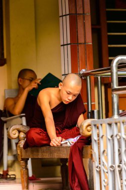 Inwa, Myanmar - 25 Ağustos 2016: Tanımlanamayan Birmanyalı Budist keşiş bir kitap okuyor. Myanma halkının yüzde 68'i Bamar etnik grubuna mensandı