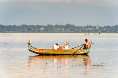 Taungthaman Gölü, Myanmar - 25 Ağustos 2016: Kimliği belirsiz Birmanyalı adam, Myanmar'ın eski başkenti Amarapura yakınlarındaki Taungthaman Gölü üzerinde turistlerle birlikte bir tekneyle yelken açtı