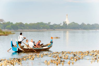 Taungthaman Gölü, Myanmar - 25 Ağustos 2016: Kimliği belirsiz Birmanyalı adam, Myanmar'ın eski başkenti Amarapura yakınlarındaki Taungthaman Gölü üzerinde turistlerle birlikte bir tekneyle yelken açtı