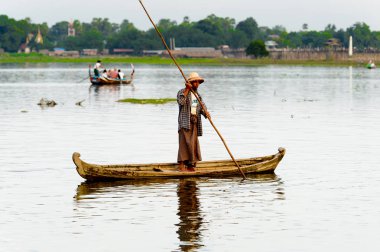 Taungthaman Gölü, Myanmar - 25 Ağustos 2016: Myanmar'ın eski başkenti Amarapura yakınlarındaki Taungthaman Gölü üzerinde seyreden bir teknedeki kimliği belirsiz Birmanyalı adam
