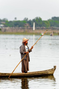 Taungthaman Gölü, Myanmar - 25 Ağustos 2016: Myanmar'ın eski başkenti Amarapura yakınlarındaki Taungthaman Gölü üzerinde seyreden bir teknedeki kimliği belirsiz Birmanyalı adam