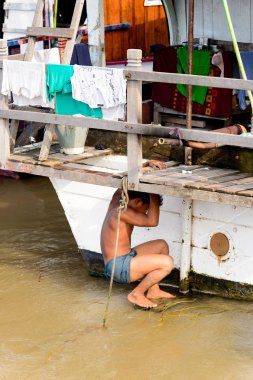 Mandalay, Myanmar - 26 Ağustos 2016: Tanımlanamayan Birmanyalı çocuk tekne motorunu çimlerden temizliyor. Myanma halkının yüzde 68'i Bamar etnik grubuna mensandı