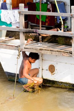 Mandalay, Myanmar - 26 Ağustos 2016: Tanımlanamayan Birmanyalı çocuk tekne motorunu çimlerden temizliyor. Myanma halkının yüzde 68'i Bamar etnik grubuna mensandı