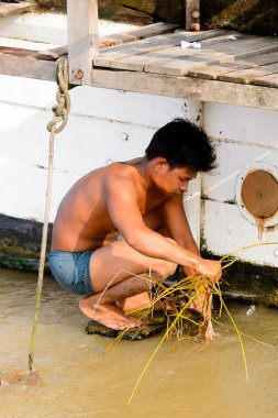 Mandalay, Myanmar - 26 Ağustos 2016: Tanımlanamayan Birmanyalı çocuk tekne motorunu çimlerden temizliyor. Myanma halkının yüzde 68'i Bamar etnik grubuna mensandı