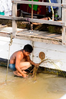 Mandalay, Myanmar - 26 Ağustos 2016: Tanımlanamayan Birmanyalı çocuk tekne motorunu çimlerden temizliyor. Myanma halkının yüzde 68'i Bamar etnik grubuna mensandı