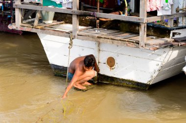 Mandalay, Myanmar - 26 Ağustos 2016: Tanımlanamayan Birmanyalı çocuk tekne motorunu çimlerden temizliyor. Myanma halkının yüzde 68'i Bamar etnik grubuna mensandı