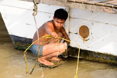 Mandalay, Myanmar - 26 Ağustos 2016: Tanımlanamayan Birmanyalı çocuk tekne motorunu çimlerden temizliyor. Myanma halkının yüzde 68'i Bamar etnik grubuna mensandı