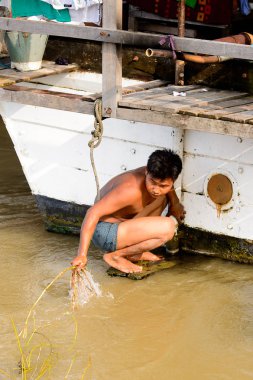 Mandalay, Myanmar - 26 Ağustos 2016: Tanımlanamayan Birmanyalı çocuk tekne motorunu çimlerden temizliyor. Myanma halkının yüzde 68'i Bamar etnik grubuna mensandı