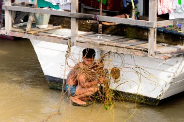 Mandalay, Myanmar - 26 Ağustos 2016: Tanımlanamayan Birmanyalı çocuk tekne motorunu çimlerden temizliyor. Myanma halkının yüzde 68'i Bamar etnik grubuna mensandı
