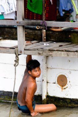 Mandalay, Myanmar - 26 Ağustos 2016: Tanımlanamayan Birmanyalı çocuk tekne motorunu çimlerden temizliyor. Myanma halkının yüzde 68'i Bamar etnik grubuna mensandı