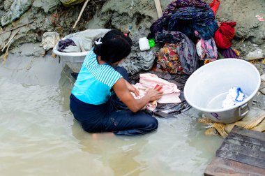 Mandalay, Myanmar - 26 Ağustos 2016: Kimliği belirsiz Birmanyalı kadın sudaki kıyafetleri temizliyor. Myanma halkının yüzde 68'i Bamar etnik grubuna mensandı