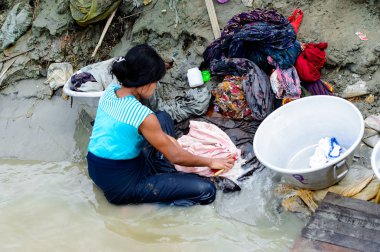 Mandalay, Myanmar - 26 Ağustos 2016: Kimliği belirsiz Birmanyalı kadın sudaki kıyafetleri temizliyor. Myanma halkının yüzde 68'i Bamar etnik grubuna mensandı