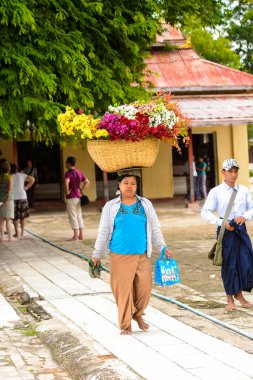 Bagan, Myanmar - 29 Ağustos 2016: Kimliği belirsiz Birmanyalı kadın başında bir sepet çiçek taşıyor. Myanma halkının yüzde 68'i Bamar etnik grubuna mensandı