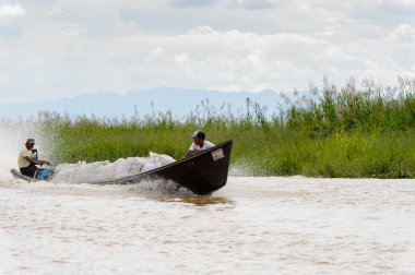 Inle Lake, Myanmar - 30 Ağustos 2016: Myanmar'ın Shan Eyaletinin Taunggyi İlçesi'nin Nyaungshwe İlçesi'nde bulunan bir tatlı su gölü olan Inle Sap'ın üzerinde bambu teknede bulunan tanımlanamayan Birmanyalı adam