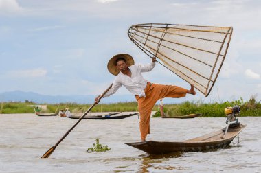 Inle Lake, Myanmar - 30 Ağustos 2016: Tanımlanamayan Birmanyalı balıkçı, özel el yapımı ağı olan bir teknede dengeyapıyor. Bu Myanmar balıkçılık geleneksel yoludur