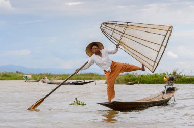 Inle Lake, Myanmar - 30 Ağustos 2016: Tanımlanamayan Birmanyalı balıkçı, özel el yapımı ağı olan bir teknede dengeyapıyor. Bu Myanmar balıkçılık geleneksel yoludur