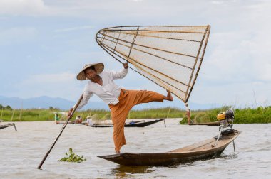 Inle Lake, Myanmar - 30 Ağustos 2016: Tanımlanamayan Birmanyalı balıkçı, özel el yapımı ağı olan bir teknede dengeyapıyor. Bu Myanmar balıkçılık geleneksel yoludur