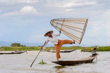 Inle Lake, Myanmar - 30 Ağustos 2016: Tanımlanamayan Birmanyalı balıkçı, özel el yapımı ağı olan bir teknede dengeyapıyor. Bu Myanmar balıkçılık geleneksel yoludur