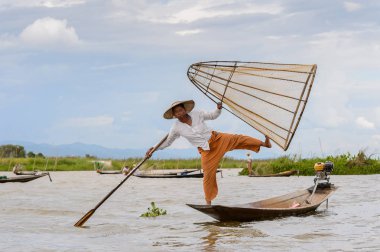 Inle Lake, Myanmar - 30 Ağustos 2016: Tanımlanamayan Birmanyalı balıkçı, özel el yapımı ağı olan bir teknede dengeyapıyor. Bu Myanmar balıkçılık geleneksel yoludur