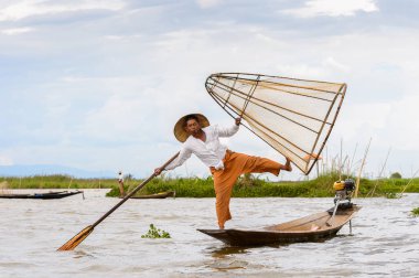 Inle Lake, Myanmar - 30 Ağustos 2016: Tanımlanamayan Birmanyalı balıkçı, özel el yapımı ağı olan bir teknede dengeyapıyor. Bu Myanmar balıkçılık geleneksel yoludur