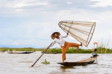 Inle Lake, Myanmar - 30 Ağustos 2016: Tanımlanamayan Birmanyalı balıkçı, özel el yapımı ağı olan bir teknede dengeyapıyor. Bu Myanmar balıkçılık geleneksel yoludur