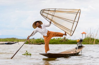 Inle Lake, Myanmar - 30 Ağustos 2016: Tanımlanamayan Birmanyalı balıkçı, özel el yapımı ağı olan bir teknede dengeyapıyor. Bu Myanmar balıkçılık geleneksel yoludur