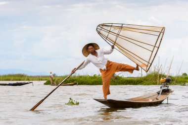 Inle Lake, Myanmar - 30 Ağustos 2016: Tanımlanamayan Birmanyalı balıkçı, özel el yapımı ağı olan bir teknede dengeyapıyor. Bu Myanmar balıkçılık geleneksel yoludur