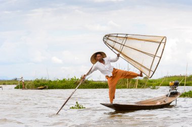 Inle Lake, Myanmar - 30 Ağustos 2016: Tanımlanamayan Birmanyalı balıkçı, özel el yapımı ağı olan bir teknede dengeyapıyor. Bu Myanmar balıkçılık geleneksel yoludur