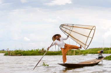 Inle Lake, Myanmar - 30 Ağustos 2016: Tanımlanamayan Birmanyalı balıkçı, özel el yapımı ağı olan bir teknede dengeyapıyor. Bu Myanmar balıkçılık geleneksel yoludur