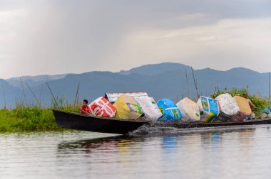 Inle Lake, Myanmar - 30 Ağustos 2016: Shan Eyaleti'nin Taunggyi İlçesi Nyaungshwe İlçesi'nde bulunan bir tatlı su gölü olan Inle Sap'ın üzerinde çantalı bambu teknede tanımlanamayan Birmanyalı adam