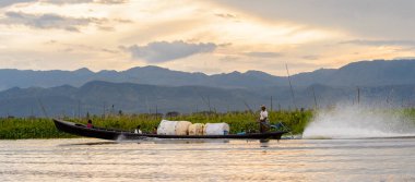 Inle Lake, Myanmar - 30 Ağustos 2016: Shan Eyaleti'nin Taunggyi İlçesi Nyaungshwe İlçesi'nde bulunan bir tatlı su gölü olan Inle Sap'ın üzerinde çantalı bambu teknede tanımlanamayan Birmanyalı adam