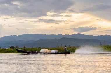 Inle Lake, Myanmar - 30 Ağustos 2016: Shan Eyaleti'nin Taunggyi İlçesi Nyaungshwe İlçesi'nde bulunan bir tatlı su gölü olan Inle Sap'ın üzerinde çantalı bambu teknede tanımlanamayan Birmanyalı adam