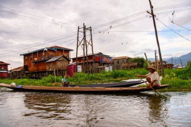 Inle Lake, Myanmar - 30 Ağustos 2016: Shan Eyaleti'nin Taunggyi İlçesi Nyaungshwe İlçesi'nde bulunan bir tatlı su gölü olan Inle Sap'ın üzerinde çantalı bambu teknede tanımlanamayan Birmanyalı adam