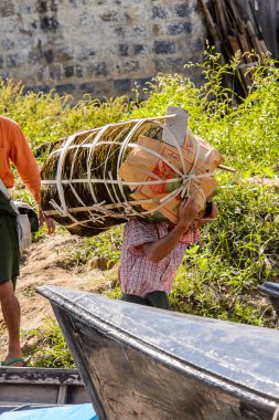 Inle Lake, Myanmar - 30 Ağustos 2016: Kimliği belirsiz Birmanyalı adam, Shan Eyaleti'nin Taunggyi İlçesi'nin Nyaungshwe İlçesi'ndeki tatlı su gölü Inle Sap'ın üzerinde bambu teknesinde eşya taşıyor.
