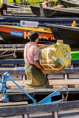 Inle Lake, Myanmar - 30 Ağustos 2016: Kimliği belirsiz Birmanyalı adam, Shan Eyaleti'nin Taunggyi İlçesi'nin Nyaungshwe İlçesi'ndeki tatlı su gölü Inle Sap'ın üzerinde bambu teknesinde eşya taşıyor.