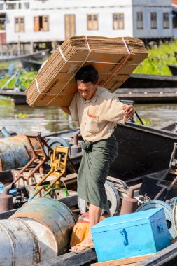 Inle Lake, Myanmar - 30 Ağustos 2016: Kimliği belirsiz Birmanyalı adam, Shan Eyaleti'nin Taunggyi İlçesi'nin Nyaungshwe İlçesi'ndeki tatlı su gölü Inle Sap'ın üzerinde bambu teknesinde eşya taşıyor.