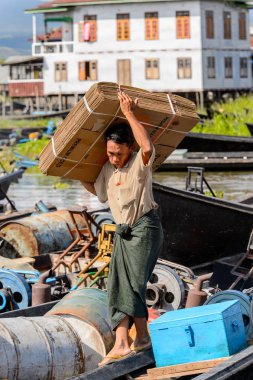Inle Lake, Myanmar - 30 Ağustos 2016: Kimliği belirsiz Birmanyalı adam, Shan Eyaleti'nin Taunggyi İlçesi'nin Nyaungshwe İlçesi'ndeki tatlı su gölü Inle Sap'ın üzerinde bambu teknesinde eşya taşıyor.