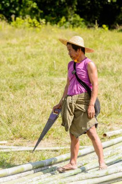 Inle Lake, Myanmar - 30 Ağustos 2016: Kimliği belirsiz Birmanyalı adam testereyle yürüyor. Myanma halkının yüzde 68'i Bamar etnik grubuna mensandı