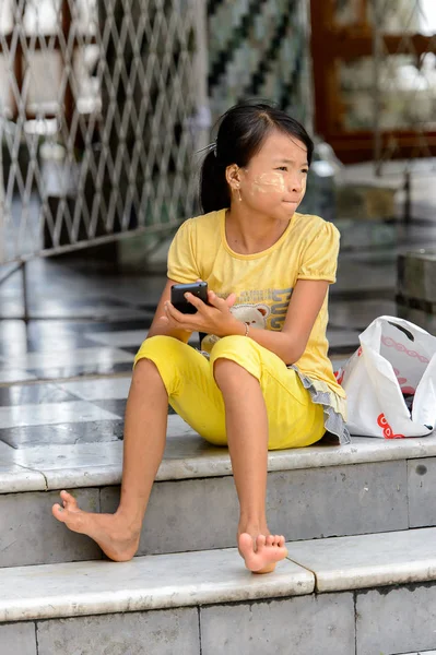 Yangon, Myanmar - 24 Ağustos 2016: Tanımlanamayan Birmanyalı Budist kız telefonuyla oynuyor. Myanma halkının yüzde 68'i Bamar etnik grubuna mensandı