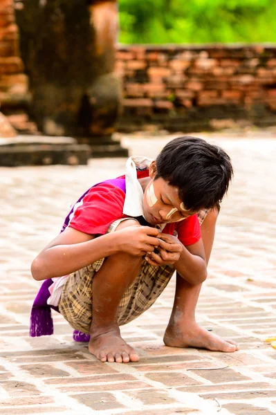 Inwa, Myanmar - 25 Ağustos 2016: Tanımlanamayan Birmanyalı genç çocuk yerde oynuyor. Myanma halkının yüzde 68'i Bamar etnik grubuna mensandı