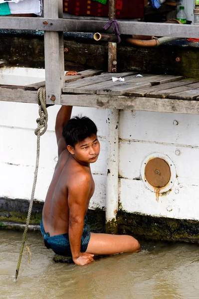 Mandalay, Myanmar - 26 Ağustos 2016: Tanımlanamayan Birmanyalı çocuk tekne motorunu çimlerden temizliyor. Myanma halkının yüzde 68'i Bamar etnik grubuna mensandı