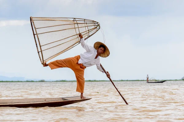 Inle Lake, Myanmar - 30 Ağustos 2016: Tanımlanamayan Birmanyalı balıkçı, özel el yapımı ağı olan bir teknede komik bir duruş sergiliyor. Bu Myanmar balıkçılık geleneksel yoludur