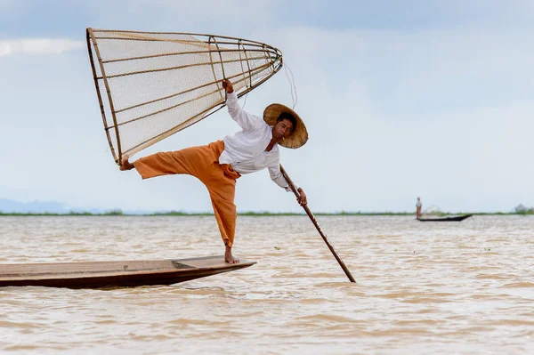 Inle Lake, Myanmar - 30 Ağustos 2016: Tanımlanamayan Birmanyalı balıkçı, özel el yapımı ağı olan bir teknede komik bir duruş sergiliyor. Bu Myanmar balıkçılık geleneksel yoludur