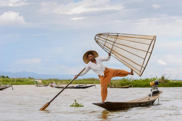 Inle Lake, Myanmar - 30 Ağustos 2016: Tanımlanamayan Birmanyalı balıkçı, özel el yapımı ağı olan bir teknede dengeyapıyor. Bu Myanmar balıkçılık geleneksel yoludur