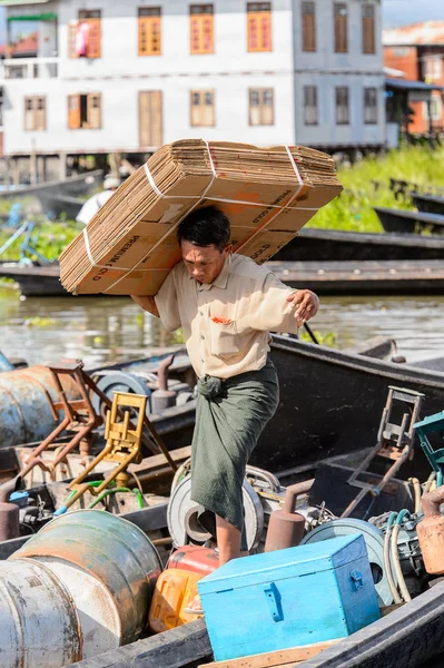 Inle Lake, Myanmar - 30 Ağustos 2016: Kimliği belirsiz Birmanyalı adam, Shan Eyaleti'nin Taunggyi İlçesi'nin Nyaungshwe İlçesi'ndeki tatlı su gölü Inle Sap'ın üzerinde bambu teknesinde eşya taşıyor.