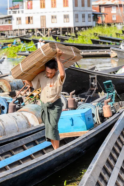 Inle Lake, Myanmar - 30 Ağustos 2016: Kimliği belirsiz Birmanyalı adam, Shan Eyaleti'nin Taunggyi İlçesi'nin Nyaungshwe İlçesi'ndeki tatlı su gölü Inle Sap'ın üzerinde bambu teknesinde eşya taşıyor.